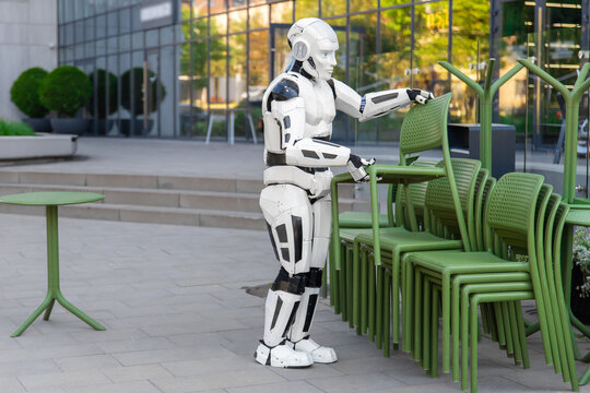 Full length humanoid robot carrying stacked chairs