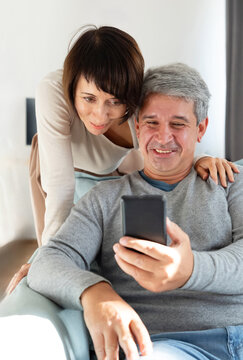 Mature couple share smartphone moment at home together