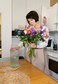 Woman arrange fresh flower bouquet in home kitchen