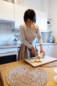 Woman slice bread in home kitchen for meal preparation