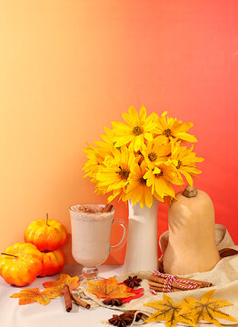 Warming pumpkin latte with cinnamon and star anise, pumpkin and fallen leavesSeasonal abstract composition with hot autumn drink and rudbeckia flowers, , banner for screen, autumn greeting concept