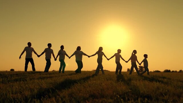 Large group people strolling on grass in sun. Parents children, holding hands, play in park. Happy family outing. Dad mom children playing outdoors. People holding hands, Dream Family, silhouette.