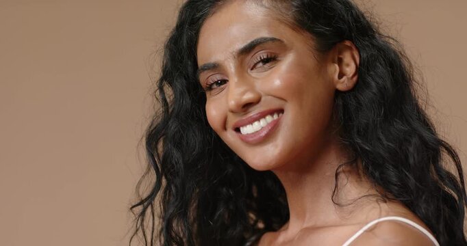 Indian woman on cue turning to camera, opening eyes, smiling wider in thin-strap top