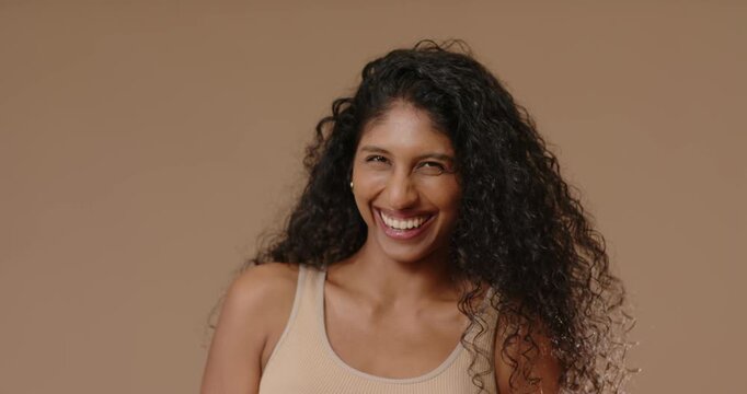 African American woman laughing and leaning toward camera in studio, wearing ribbed tank