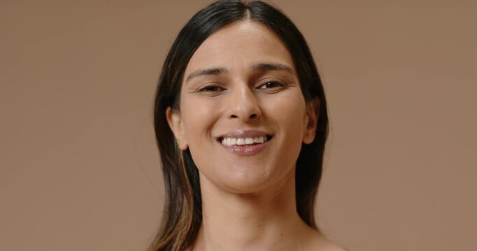 adult Indian woman following cue, smiling then laughing for photoshoot, in off-white top