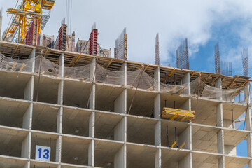 Construction site showcasing the progress of a high-rise building with steel reinforcements under a blue sky © beholdereye