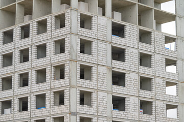 Construction of a tall building showcases a blend of modern architecture and raw materials in a bustling urban area © beholdereye