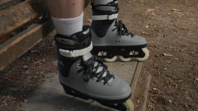 Rollerblader resting on a bench with his skates in a park