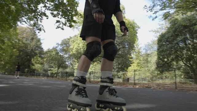 A skater speeds up in Battersea Park, London on a sunny autumn day with his rollerblades 