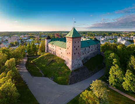 aerial view of turku castle at morning sun with green springtime trees and park in turku finland