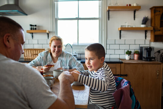 Parents and son eating breakfast in a home kitchen