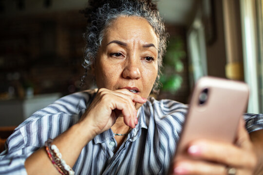 Concerned middle-aged woman reading message at home