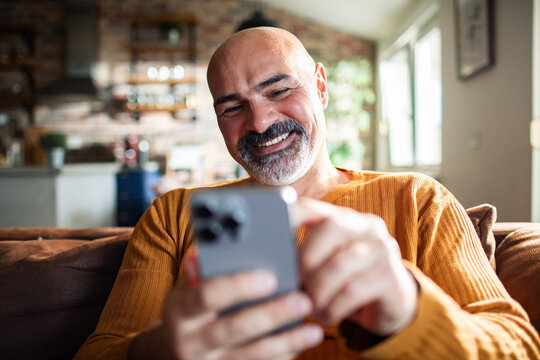 Mature man using smartphone on sofa at home
