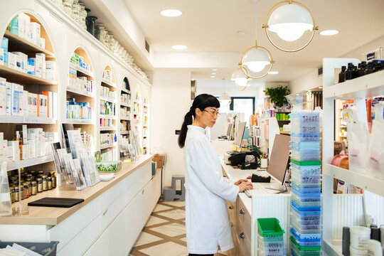 Female pharmacist working at computer in modern pharmacy