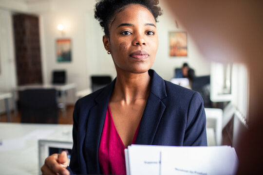 Confident businesswoman holding reports in modern office