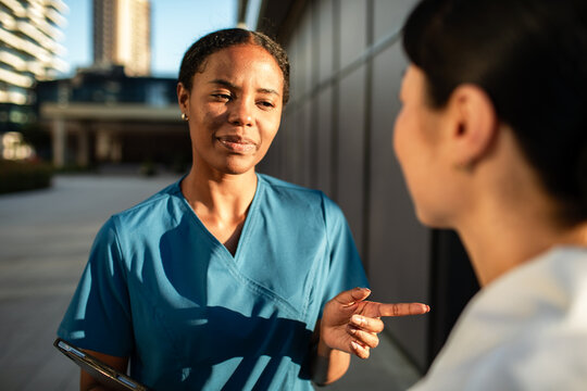 Nurse giving instructions to colleague outside hospital building