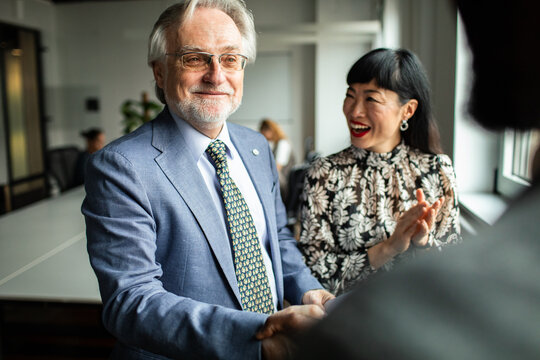Senior executive shaking hands after meeting in modern office