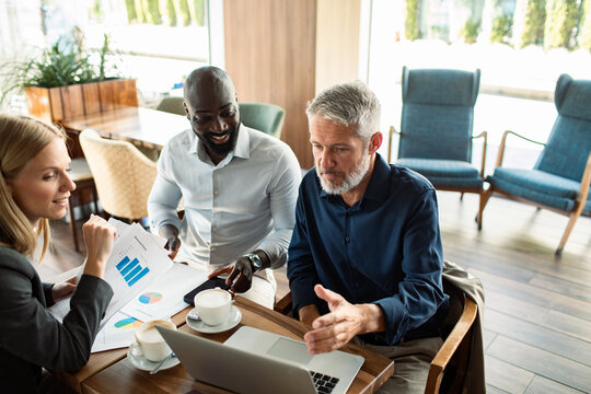 Business colleagues discussing charts on laptop in coffee shop