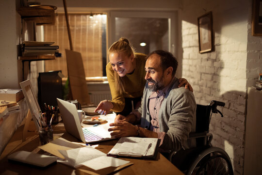 Couple collaborating on laptop at home office, wheelchair user