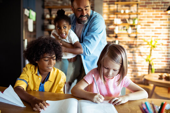 Father with children doing homework in home kitchen