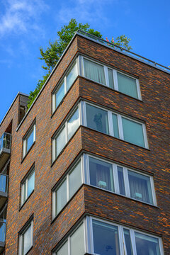 Low angle view of modern brick apartment building with rooftop garden.