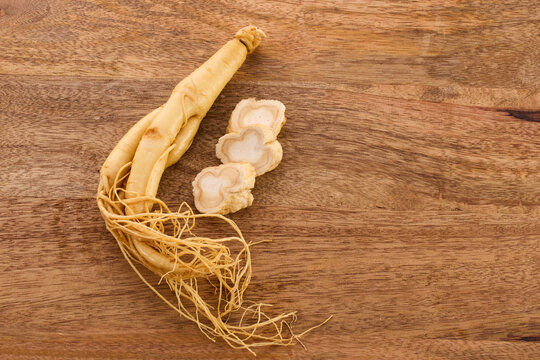 Ginseng root with sliced pieces on wood