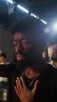 African American man closes his eyes and places a hand on his heart during worship in an evangelical church, expressing faith, heartfelt prayer and spiritual surrender