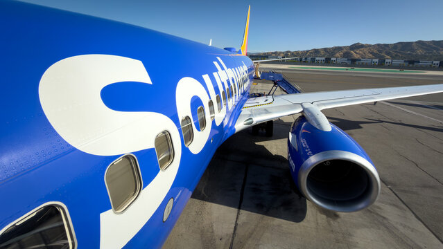 BURBANK, CA, APR 28, 2026: Close-up wide angle view of Southwest Airlines Boeing 737 fuselage showing large "Southwest" logo lettering, windows, engine, wing, and distant mountains, Burbank Airport