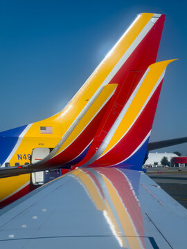 BURBANK, CA, APR 28, 2026: Vertical close-up of overlapping Southwest Airlines aircraft tail fins with vivid red, yellow, blue livery, American flag decal, and distant buildings at Burbank Airport