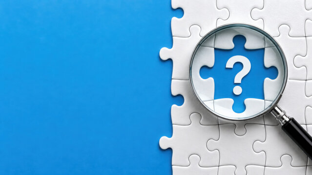 Magnifying glass over a white jigsaw puzzle with a question mark on a blue background representing problem solving