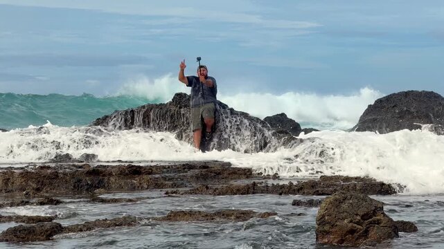 Man taking a selfie is surprised by a huge ocean wave