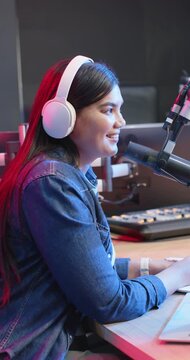 Vertical video: African American woman hosting podcast speaking laughing smiling into mic in studio