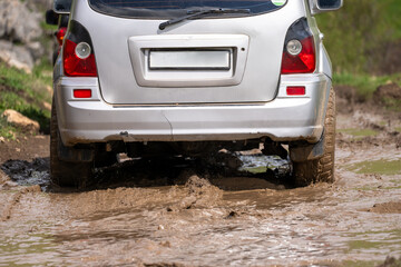 The car drives on a muddy, bad off-road road. © Daniel