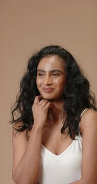 Vertical video: On cue Indian woman posing, changing smile in studio wearing white top for portrait