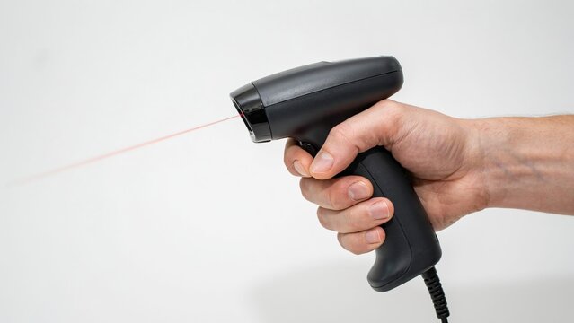 Black barcode scanner held in hand emitting a red laser beam against a plain white surface