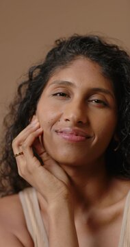 Vertical video: Woman resting chin on hand, thinking then smiling and laughing in studio with ring