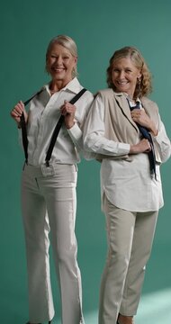 Vertical video: Senior female models taking cue for shoot, posing in studio, wearing white shirts