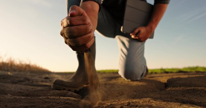 Agronomist examining the quality of dry soil, pouring it from his hand. Arid land suffering from drought and climate change effects