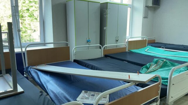 Spacious hospital room with multiple beds and bright windows prepared for patients.