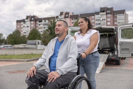 Manual wheelchair user enjoying an outdoor stroll with a Personal assistant while chatting, smiling, and spending quality time together.