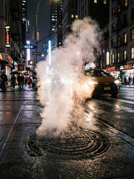 Steam rising from NYC street manhole at night with yellow taxi