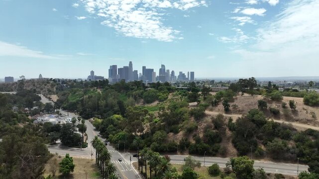 Los Angeles, California, USA - Pullback Drone Aerial View of Downtown Skyline From Elysian Park With Tall Trees, Green Hilltops and Urban Cityscape in Daytime