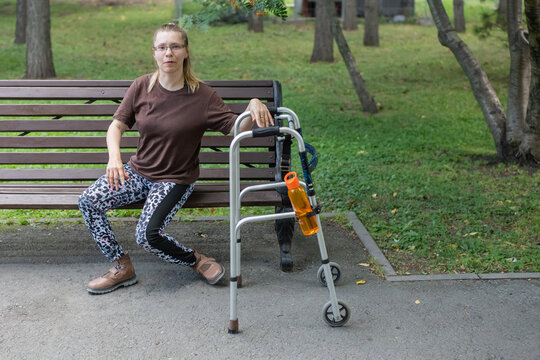 A Caucasian woman with cerebral palsy sits on a park bench.