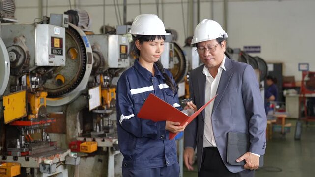 Female engineer and male manager industrial factory safety helmet conducting technical inspection of machinery and industrial equipment, supporting workplace collaboration, manufacturing review