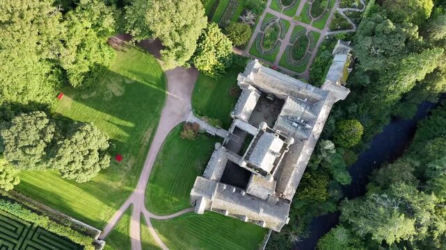 Top down aerial drone footage overhead Cawdor Castle, parterre garden, hedge maze, and surrounding estate in Nairnshire, Scottish Highlands, Scotland