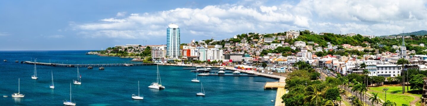 A panoramic view of the harbor, waterfront, and skyline of Fort-de-France with sailboats on the Caribbean Sea in Martinique.