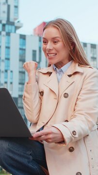 Overjoyed happy mature businesswoman working on laptop netbook screaming in delight triumph winner gesture celebrate success game money win outdoors. Happy adult girl woman on downtown city street.