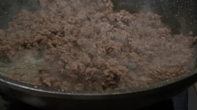 Ground beef browning in dark pan during cooking process showing minced meat texture and preparation for meal