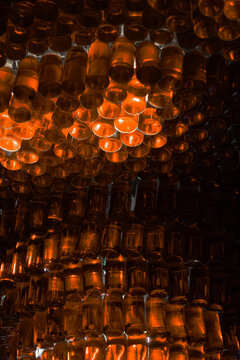 Red bottle pattern. Glowing glass array. Ruby liquor texture. Crimson alcohol background. Dark tincture backdrop. Illuminated beverage wall. Abstract spirit grid. Backlit liquid display. Scarlet
