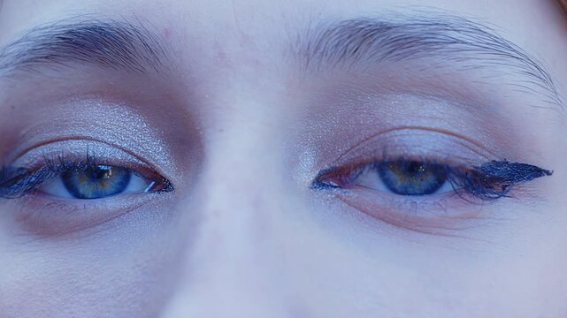 A beautiful girl with sensual light blue eyes stares intently at the camera in a close-up shot.
